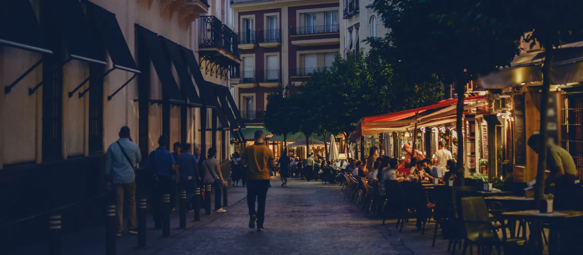 Calle peatonal del centro de Sevilla al anochecer, con terrazas iluminadas